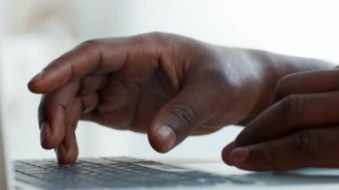 Genç bir Afrikalı Amerikalı evdeki dizüstü bilgisayarına odaklanmış, teknolojiyle etkileşim kurarken daktilo ediyor. Dikkati, kullandığı cihazla derin bir bağ kurduğunu gösteriyor..