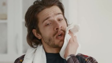 Genç bir adam evde egzersiz yapıyor, egzersiz rutinini tamamlıyor. Yüzündeki teri bir havluyla siliyor. Kendini spora ve sağlığa adadığını gösteriyor..