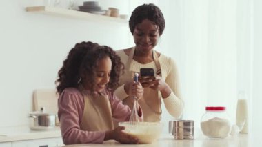 Bir anne ve kızı, sıcak mutfaklarında keyifli bir yemek pişirme seansının keyfini çıkarırlar. İçindekileri karıştırırken aynı zamanda gülümseme ve kahkahaları paylaşırlar. Aralarındaki bağ bu eğlenceli aktiviteyle güçlenir..