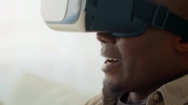 Bir adam oturma odasında dijital bir dünyaya dalmış sanal gerçeklik teknolojisiyle meşgul olur. Ayarlar modern ev yaşamını yansıtıyor, aletlerin eğlence zamanı üzerindeki etkisini gösteriyor..