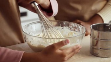 Bir anne ve kızı evlerinin mutfağında neşe içinde yemek pişiriyorlar. Malzemeleri bir kasede karıştırıyorlar, tatlı hamur işleri yapıyorlar ve birlikte vakit geçiriyorlar..