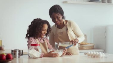 Sıcak bir mutfakta, bir anne ve kızı hamur işi pişirirken birlikte güzel vakit geçiriyorlar..