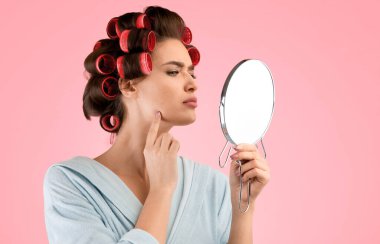 Sivilce sorunu. Kıvırcık saçlı endişeli bir kadın yuvarlak aynaya bakıyor ve sarı stüdyo geçmişine bakan sivilceli bir kadın. Cilt Tedavisi ve Bakımı, Kozmetik Konsepti