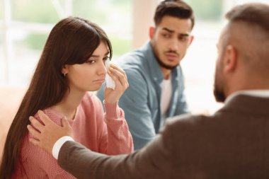 Terapi seansı sırasında ağlayan kadını teselli eden evlilik danışmanı, sorunlarını paylaşırken duygusal çöküntüye uğrayan kadın, kocasıyla birlikte psikolog ofisinde oturan kadın.