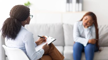 Depresyondaki siyahi kadın, zihinsel klinikten profesyonel psikolojik yardım alıyor, seçici odaklanma. Kadın psikoterapist çaresiz Afro kadınla seans yapıyor. Travma sonrası stres bozukluğu ya da duygusal travma.