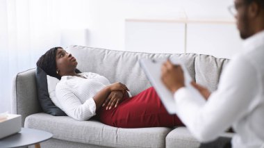 Genç siyahi bir kadının psikologla randevusu var, ofiste koltukta uzanıyor, profesyonel sorunlarıyla ilgili danışmanlık yapıyor. Klinikteki psikoterapistle iletişim kuran Millennial kadın hasta