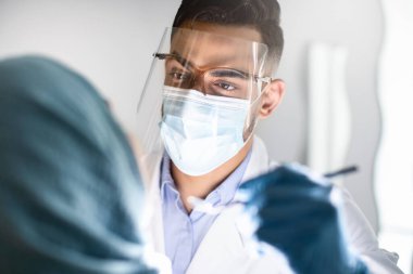 Arap Adam Diş Hekimi Koruyucu Tıbbi Maske ve Yüz Koruyucu Kalkanında, Müslüman Kadın Dişleri İnceleme, Stomatolog Doktor Diş Hekimliği, Diş Hekimliği, Kapanış