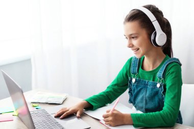 Evde ders çalışıyorum. Neşeli liseli kız ödevlerini yapıyor ve klavyede daktilo kullanıyor, dizüstü bilgisayarla masaya oturuyor, ekrana bakıyor, deneme yazıyor ya da test yapıyor, ders kitabından notlar alıyor, bedava fotokopi çekiyor.