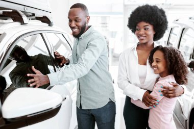 Otomobil galerisinde yeni araba seçen mutlu siyahi aile. Afro-Amerikalı müşteriler kiralamak ya da almak için lüks otomobil seçiyorlar. Araç yerel dağıtım kavramı