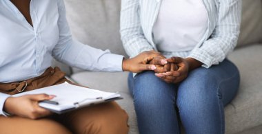 Depresyondaki insanlar için profesyonel yardım. Kadın hastaya psikolojik yardım sağlayan terapist, klinikte elini tutuyor, görüşünü kırpıyor. Duygusal ve zihinsel bozuklukların tedavisi