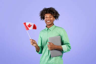 Modern eğitim ve öğrenci değişimi. Kanada 'nın küçük bayrağını elinde tutan mutlu siyah adam ve kameraya gülümsüyor, mavi arka planda duruyor, stüdyo çekimi, kopyalama alanı