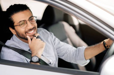 Gülümseyen, uzun saçlı, gözlüklü, yeni arabasının keyfini çıkaran, mutlu, orta doğulu genç adam. Arabasını ofisten ofise sürüyor, fotokopi alanına bakıyor, yakın plan portresi çekiyor. Araba, otomobil, araç kokusu