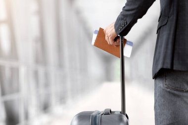 Hava Yolları Konsepti. Pasaportu ve uçak biletleri olan bir adamın yakın plan fotoğrafı Arport Terminali 'nde uçak bileti bekleyen tanınmayan bir erkek yolcu, arka manzara, kesilmiş resim.