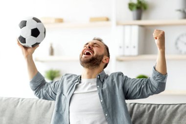 Duygusal beyaz adam televizyonda futbol seyrediyor, topu kafasının üstüne kaldırıyor ve bağırıyor, golü veya zaferi evde kutluyor. Havalı genç adam televizyonda en sevdiği futbol takımını destekliyor.