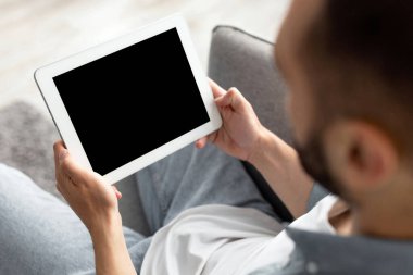 Evde ekranı boş olan tablet bilgisayarda çalışan tanınmayan genç adam web sitesi ya da uygulama tasarımı için modelleme yapıyor. Bin yıllık adamın elinde dokunmatik ped, reklam için yer tuttuğu yakın plan.