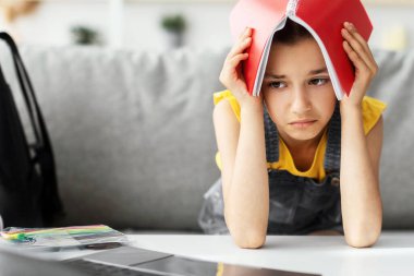 Bir sürü ev ödevi konsepti. Kafasına dizüstü bilgisayarı dayayıp tutan yorgun öğrenci portresi. Evde uzaktan eğitim gören genç, seçici odaklanma, boş alan.