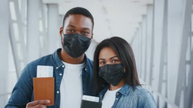 İki Afro-Amerikan milenyumu seyahat belgelerini gururla bir havaalanında tutuyor. Maske takıyorlar, salgın sırasında devam eden turizm sorunlarını sergiliyorlar..