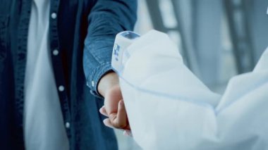 Bir sağlık uzmanı bir havaalanında sıcaklık kontrolü yaptığı için, milenyumlar yolculuklarına hazırlanıyorlar. Kapalı alan ayarları, mevcut seyahat kısıtlamaları sırasında güvenlik tedbirlerini yansıtır.