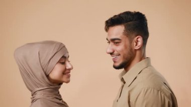 Orta Doğu 'dan genç evli bir çift stüdyo ortamında duruyor ve gülümsüyor. Kadın ve erkek bu samimi anda çok bağlı ve mutlu görünüyorlar..