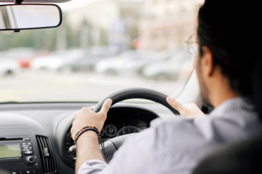 Hintli uzun saçlı deneyimli bir adamın otomobil sürüşü, yola, fotokopi alanına, otomobil arka koltuğundan çekilmiş görüntüsü, yakın plan. Tanınmayan bir Arap yeni arabasının keyfini çıkarıyor.