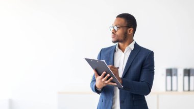 Ciddi bir siyahi psikolog, modern ofiste derin düşüncelere dalmış bir şekilde panoya yazı yazıyor. Psikoterapi hizmetleri, ruhsal sağlık profesyonel konsepti