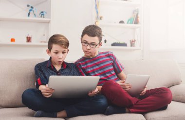 Becerikli alet ile iki erkek çocuk. Dizüstü bilgisayar ve dijital tablet evde kanepe üzerinde her komik diğer içeriği göstermesini. Çocuk dostluk ve iletişim kavramı