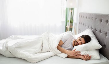 Yatma vakti. Bin yıllık Arap adam uykuda, yatak odasındaki beyaz rahat yatakta dinleniyor, kopyalama uzayı. Dinlen, rahatla, hafta sonları evde uyu..