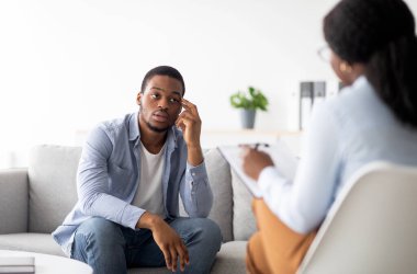 Depresyondan muzdarip stresli siyahi bir adam, danışman tıp bürosunda profesyonel yardım sağlıyor. Mutsuz erkek hasta psikologla görüşüyor, yardım alıyor.