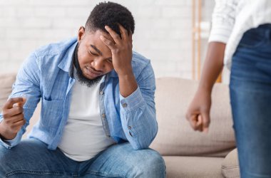 Boşanma kavramı. Karısı onu terk ederken elinde alyansla oturan yoksul siyahi adam seçici bir şekilde odaklanmış.