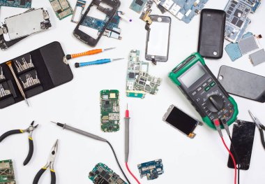 Mobil telefon tamiratı arka planda, hizmet merkezindeki iş yerinin üst görüntüsünde. Akıllı telefonun sökülmesi ve teşhisi