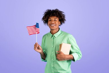Öğrenci değişimi ve İngilizce öğrenme. Zoomer, kitaplı mutlu siyah adam ve küçük Amerikan bayrağı Amerikan üniversitesine gider, mavi arka planda poz verir, stüdyo çekimi, boş alan