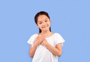 Minnettarım. Minnettar Çinli Kız Göğse Elle Bastırıyor Mor Arkaplanda Gülümseyerek Kamera Pozu Veriyor. Stüdyo Çekimi