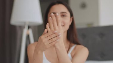Genç bir Arap kadın evde güzellik hizmetleri rutinine girişiyor. Ellerine cilt bakımı uygularken gülümsüyor. Rahatlamış ve şımarık atmosferini ön plana çıkarıyor..