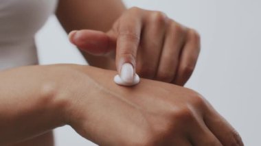 Huzurlu bir ev ortamında, genç bir Afrikalı Amerikalı kadın, cildine nemlendirici sürerek, güzelliğin ve şımartmanın önemini vurgulayarak, kendi kişisel bakım rutinine odaklanır..