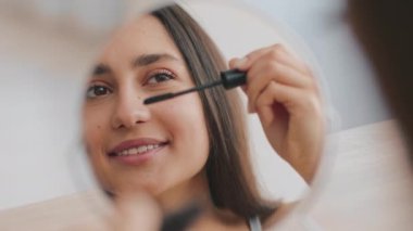 Milenyum Orta Doğulu bir kadın evdeki aynanın önünde rimel sürmeye odaklanır. Şımartma seansından zevk alıyor, doğal güzelliğini ve rahatlığını arttırıyor..