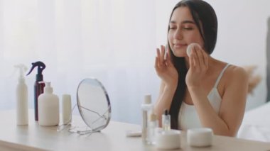 Bin yıllık Orta Doğulu bir kadın evinde kendini şımartıyor. O, aynaya bakarken cilt bakım ürünleri kullanıyor. Ayar parlak ve davetkar, gösterişli rahatlama.