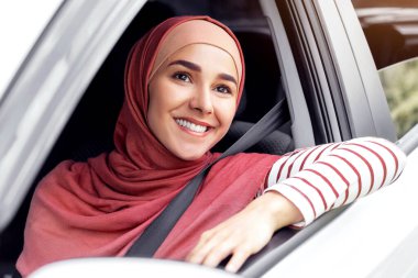 Binlerce yıllık neşeli orta yaşlı kadın sürücüyle tesettüre binmiş, açık pencereden dışarı bakıyor, seyahatin tadını çıkarıyor, açık havada, kopyalama alanında. Yazın seyahat, hafta sonu yolda yeni otomobil, tatiller