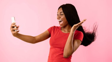 Afrikalı Amerikalı Milenyum Kadını Akıllı Telefon Kullanıyor Selfie 'yi örgülü saçlarla oynatıyor, poz veriyor ve sarı arka planda eğleniyor. Heyecanlı Kadın Video Arayan Stüdyo Fotoğrafı