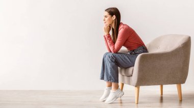 Düşünceli genç bir kadın, beyaz stüdyo duvarına karşı dalgın ve hayalci bir ifadeyle boş bir yere bakıyor. Bin yıllık bir bayanın bir şey hayal etmesi, seçim yapması ya da karar vermesi.