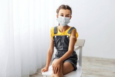 Çocuk bakımı ve okul için aşı gerekliydi. Klinikte iğne yaptıktan sonra koluna yapışkan bandaj yapıştırılmış kamera pozuna bakarken koruyucu maske takan aşılanmış gözbebeği portresi.