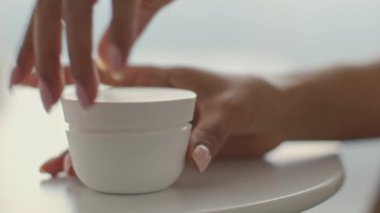 Genç bir Afrikalı Amerikalı kadın cilt bakımını evde yapar, cilt bakımı ürünü kullanır. Rahatlamış ve derisini özenle şımartmaya odaklanmış görünüyor..