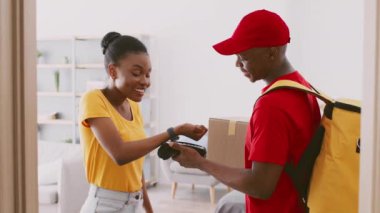 Kırmızı gömlekli ve şapkalı genç bir Afro-Amerikalı sarı gömlekli bir kadına evine paket teslim ediyor. Atmosfer sıradan ve tipik bir teslimat deneyimini yansıtıyor..