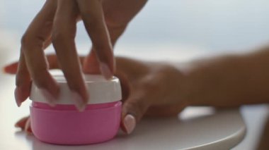 Genç bir Afrikalı Amerikalı kadın evde güzellik kremi sürüyor. Kişisel şımartma seanslarından hoşlanıyor, cilt bakımına odaklanıyor. Parlak alan rahatlatıcı atmosfere katkı sağlar..