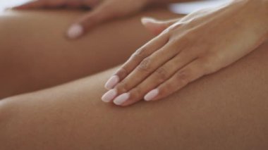 Genç bir Afrikalı Amerikalı bayan evde dinlenirken pürüzsüz cildine losyon sürüyor. Boş zamanlarında güzellik ve kendini pohpohlamayı vurgulayarak vücut bakımına odaklanıyor..