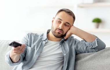Evdeki kanepede televizyon seyreden, uzaktan kumandalı, sıkılmış genç bir adam. Bin yıllık beyaz adam televizyonda kanal değiştiriyor, film ya da programla ilgilenmiyor.