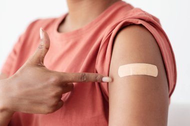 Kolundaki orta bandı işaret eden tanımlanamayan siyah kadın koronavirüse karşı aşı olurken COVID-19 salgını kesilmiş. Dokunulmazlık, aşı kavramı