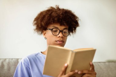 Odaklanmış Afrikalı Amerikalı ergen kitap okuyor, büyüleyici hikayenin tadını çıkarıyor. Zeki siyah öğrenci ders kitabı ile sınav ya da sınava hazırlanıyor, kapalı alanda ders çalışıyor.