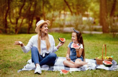 Anne ve kızı aile pikniği yapıyor, dışarıda meyve yiyor ve yaz gününün tadını çıkarıyor..