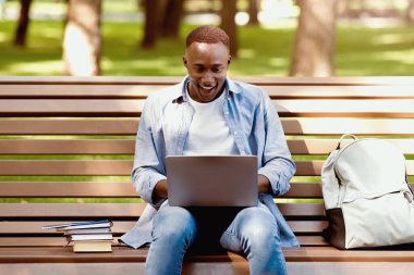 Laptop ekranına bakan heyecanlı siyahi öğrenci, onun parktaki başarısına inanamıyor. Genç Afrikalı Amerikalı çocuk zor sınavı geçtiği için mutlu, burs alıyor, mükemmel bir sınav notu alıyor.