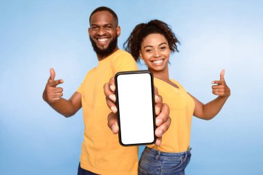 Bu yeni uygulamayı kullan. Pozitif Afro-Amerikalı çift beyaz ekranlı akıllı telefonu işaret ediyor, mobil uygulama öneriyorlar, web sitenizi tanıtıyorlar, maket yapıyorlar. Seçici odak